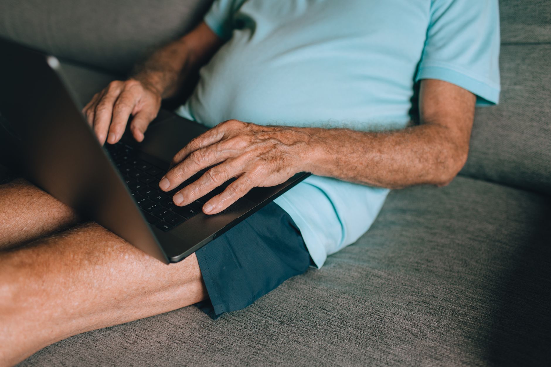 Uomo anziano compila la domanda ETA UK per over 70 al computer di casa