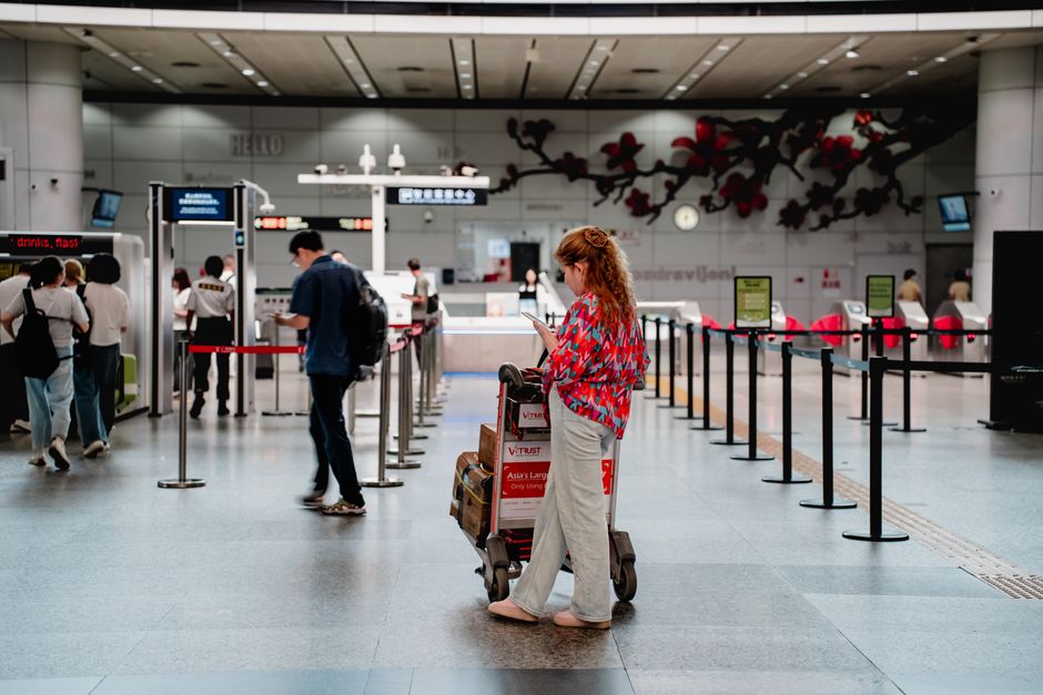 Viaggiatore con trolley in aeroporto che controlla il telefono in attesa dell'approvazione ETA