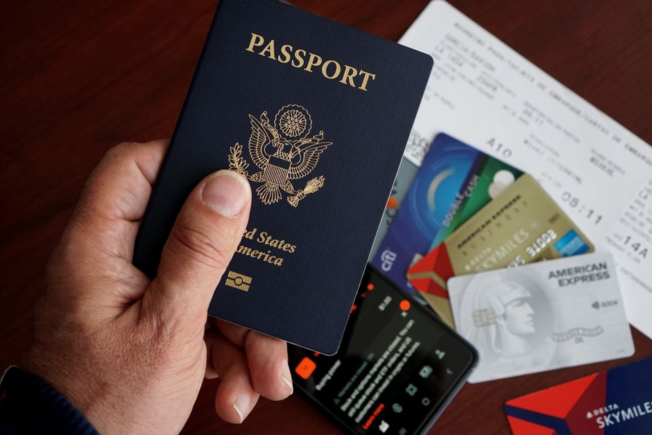 Mani che tengono passaporto e carta d'imbarco davanti al tabellone delle partenze di Londra